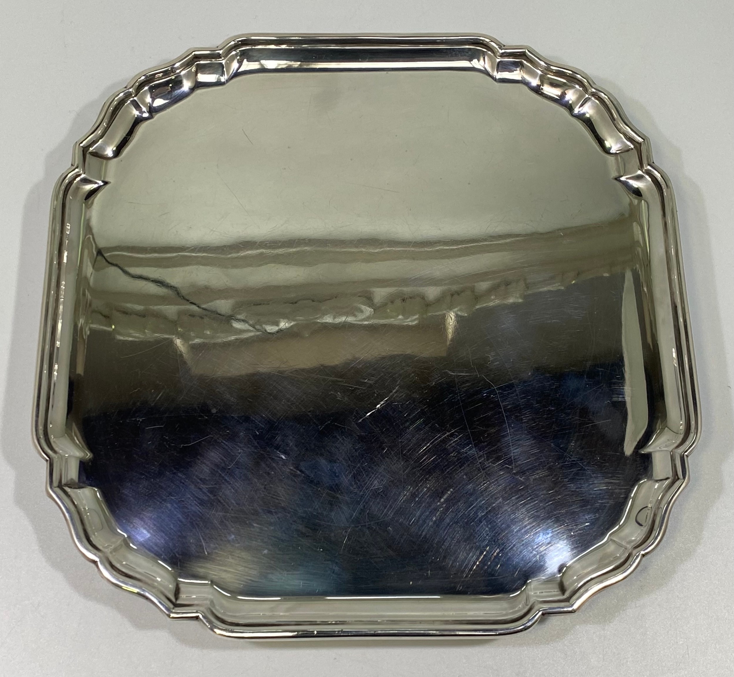 A ERII silver salver of square form with serpentine canted corners, pie-crust rim raised on four - Image 3 of 5