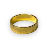 An yellow metal (high carat) wedding ring, with bark effect engraving, weighs 3.5 grams.