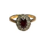 An 18ct gold oval cluster ring, set with an oval shaped red stone to the centre, with small