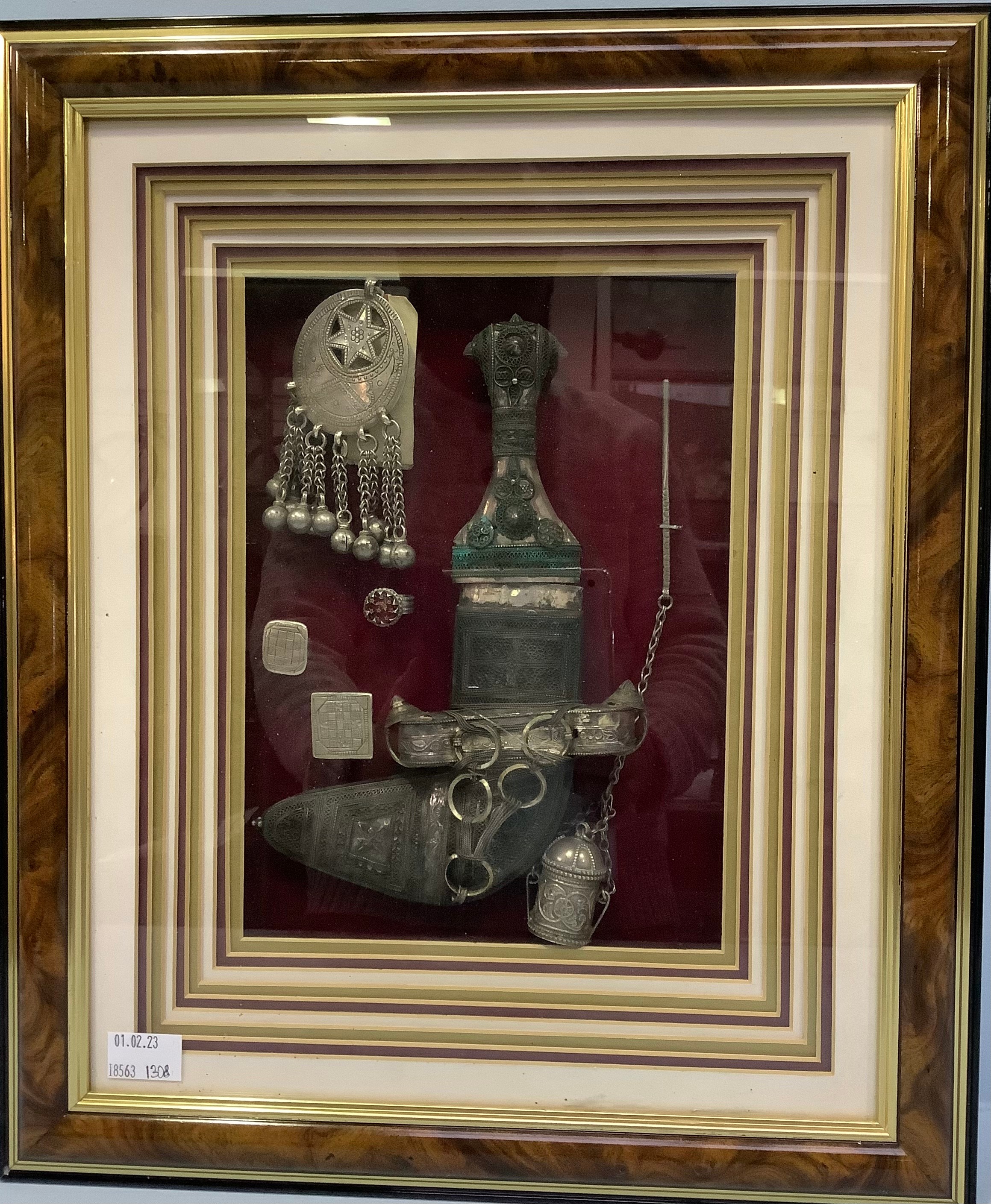 A collection of framed and mounted early 20th century Omani silver jewellery and collectables,