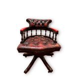 An ox-blood red leather, button-back captains chair, of typical form and with brass studding, raised