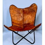 A leather butterfly chair, brown stitched slung leather cover decorated with embossed elephants,