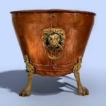 A copper coal bucket with brass lions mask ring handles and raised on lions paw feet, 43cm long