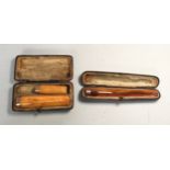 Three various amber cheroot holders, each with 9ct gold banded ends, in fitted cases
