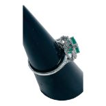 An 18ct white gold emerald and diamond ring, set with a cushion cut emerald, weighing an estimated