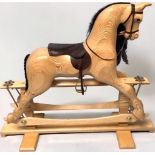 A hand-made, unpainted wooden rocking horse, lacquered with exposed grain, brown leather and brass