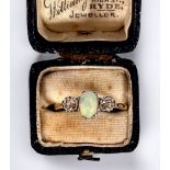 A yellow metal (tests as 18ct gold) ring, centrally claw set with an oval opal, flanked by two