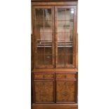 A modern reproduction two-door display cabinet with cupboards beneath, veneered in burr walnut.