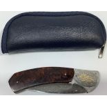A South African folding knife by John Wilmot with silver inlaid Damascus blade and wooden handle,