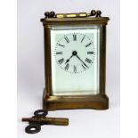 A brass carriage clock with white enamel dial and Roman numerals, spring-driven eight-day