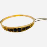 A 9ct gold bangle with garnets, some garnets missing, 7.8 grams.