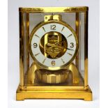 A Jaeger Le Coultre Atmos Clock, plain brass glazed case, with hinged front glass door, white enamel