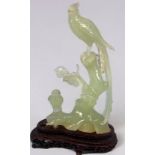 A modern carved jade figure of a pheasant and smaller bird on a branch, raised on carved wooden
