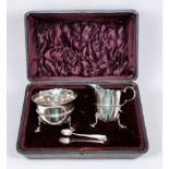 A late Victorian silver cream jug and sugar bowl with tongs, serpentine cut rims on scrolled