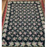 A hand-knotted fatweave floral carpet, worked with a field of roses and trellis to a black ground