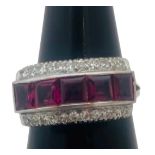 An 18ct white gold dress ring, invisible set with 5 x princess cut rubies to the centre, each ruby
