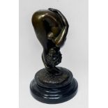 A cast and patinated bronze figure of a female nude bending in a provocative position, on circular