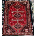 A hand-knotted oriental rug of Ashfar style, worked with three central guls to a red ground within
