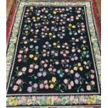 A hand-knotted flatweave carpet, worked with an all-over field of scattered flowers to a black