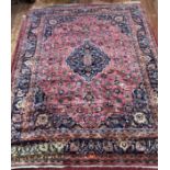 A Persian hand-knotted wool Kashan carpet, with stylised central medallion to a deep red ground,