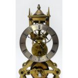 A brass skeleton clock, the silvered chapter ring with Roman numerals denoting hours, with fusee