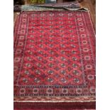 A hand-knotted wool Bokhara carpet, typically worked with stylised guls to a red ground within a