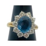 An 18ct yellow gold dress ring, set with an oval shaped, blue topaz to the centre, surrounded by