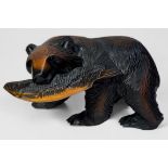 A carved and stained wooden figure of a brown bear with its fish supper, 42x25cm