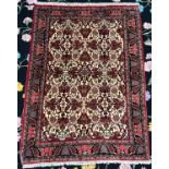 A hand-knotted oriental rug, worked with a field of herati to a biege ground with a stylised Shah