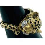 An 18ct yellow unmarked gold dress ring, cast as a stylised leopard, with black enamel spots, ruby