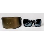 A pair of ladies Gucci sunglasses, large black wrap-around lenses and wide curved tapering arms,