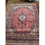 A hand-knotted Persian Kashan wool carpet, with a central medallion to a stylised floral red ground,