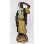 A Goldscheider painted pottery Orientalist figure of an Arab holding a jezail whilst looking yonder,