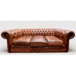 A brown leather Chesterfield sofa, low deep-button back and arms and brass studded detailing, with