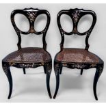 A pair of Victorian lacquered wooden chairs with open-backs and caned seats on sabre front supports,