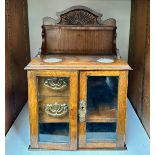 An early 20th Century oak table top/wall hanging smokers cabinet, two glazed doors open to reveal