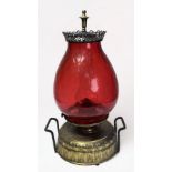 A 19th century brass oil lamp with a large cranberry glass ovoid shade