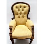 A Victorian nursing chair with yellow fabric upholstery and button back, raised on turned front