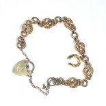 A 9ct solid gold fancy link bracelet, with 9ct gold horshoe charm, and 9ct gold heart padlock,