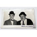 A monochrome real photographic postcard of Laurel & Hardy, signed in blue ink by Oliver Hardy, 140mm