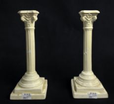 A pair of creamware pottery candlesticks modelled as classical composite columns, 30cm tall