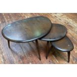 A nest of three dark stained elm pebble tables by Ercol, raised on turned and tapering supports,