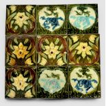 A set of nine glazed pottery fireplace surround tiles, with Art Nouveau floral decoration, some