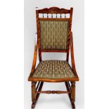 An oak rocking chair, curved wood frame, green pinstripe upholstered seat and back, a rush-seated