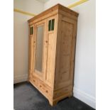 A pine wardrobe, the shaped cornice over a central bevelled mirrored door with reeded, moulded