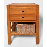 A contemporary oak chest of two drawers, above an open storage space with wicker basket, raised on