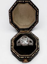 A platinum and diamond ring, rub-over set with an oval-shaped Victorian cut diamond to the centre,