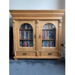 A pine bookcase top, converted to a two door cabinet, with shaped cornice above a pair of glazed