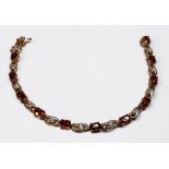 A 9ct yellow gold bracelet, claw set with 11 x oval faceted garnets, and 22 x small diamonds in