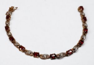 A 9ct yellow gold bracelet, claw set with 11 x oval faceted garnets, and 22 x small diamonds in